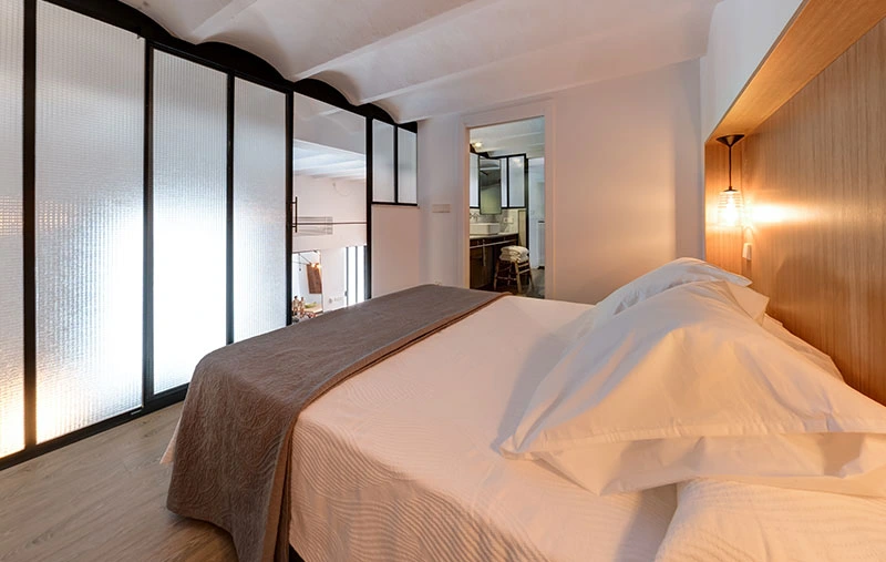 Camera da letto al livello soppalco con parete in vetro retinato e bagno privato