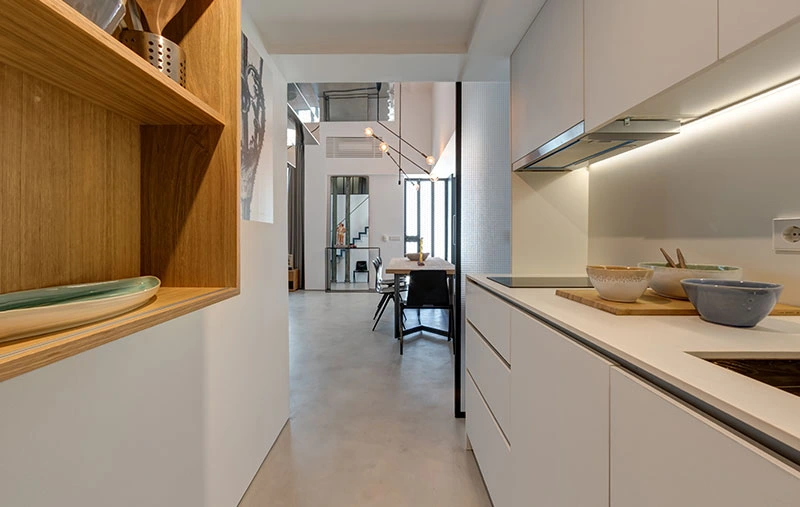 Cucina moderna bianca con mensole in legno nel loft con soppalco di Siviglia