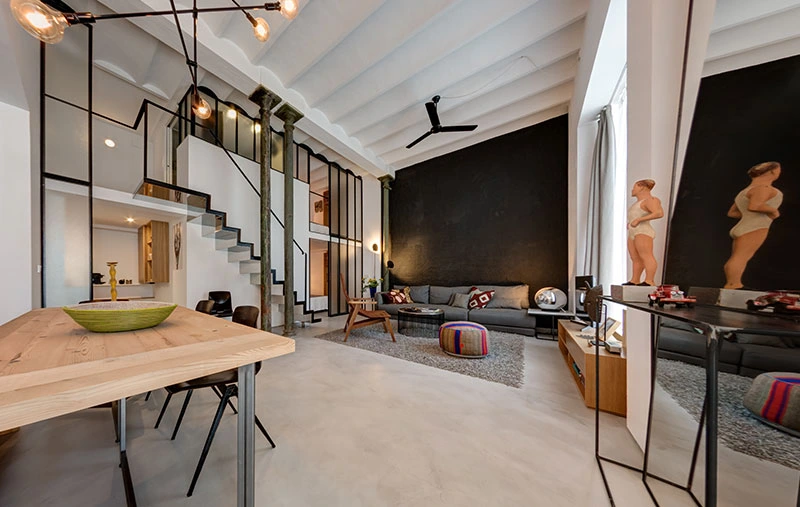 Zona giorno open space del loft con soppalco: tavolo da pranzo, salotto e scala a vista