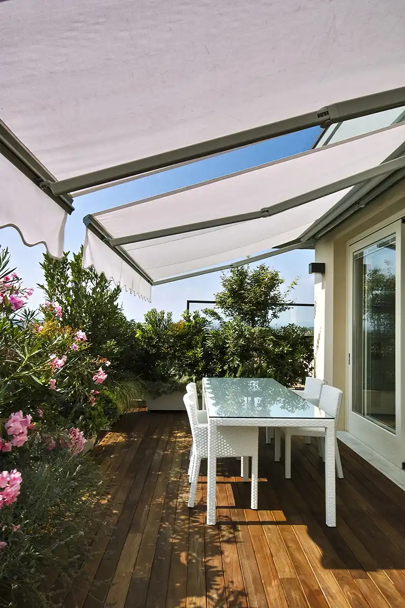 terrazzo appartamento con tavolo da pranzo ombreggiato da tende e piante