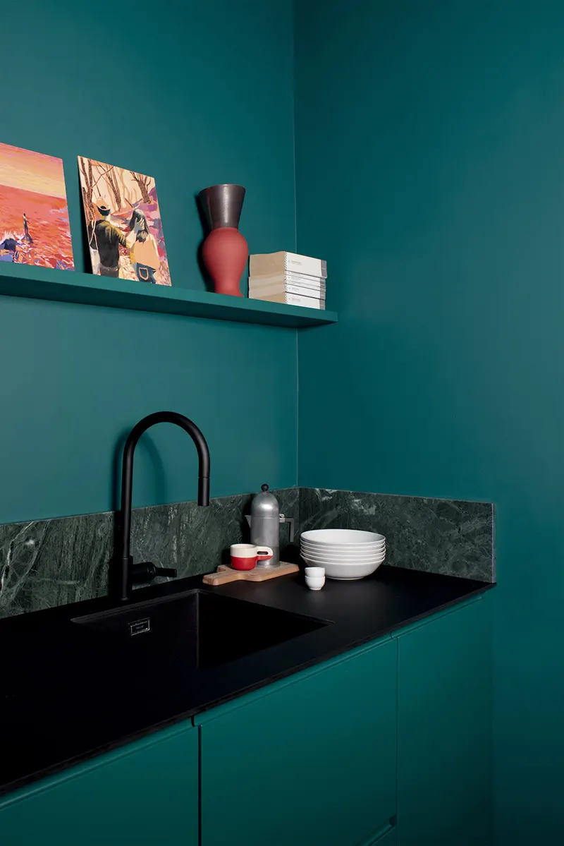 Dettaglio della cucina verde smeraldo con lavello nero, top in marmo verde e mensola con oggetti d'arredo, progetto Atelierzero per rinnovare con il colore