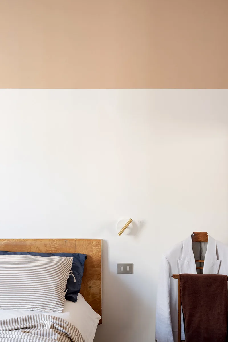 Testiera in legno vintage e parete bicolore nella camera da letto, dettaglio del progetto rinnovare con il colore