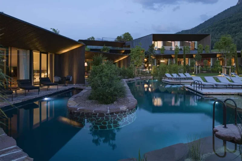Architettura del Manna Resort di Bolzano di notte con biopiscina e volumi a terrazzamenti