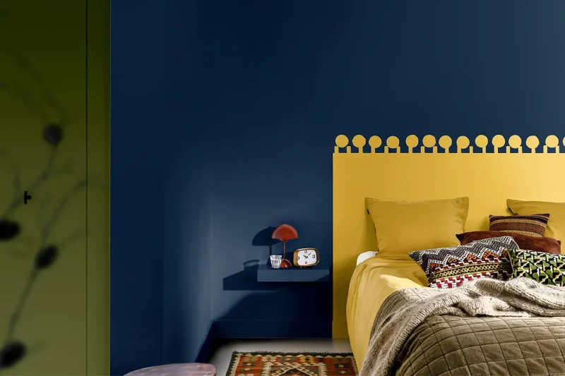 Camera da letto moderna con pareti blu e accenti giallo, dipingere casa con le tendenze colore pareti 2025