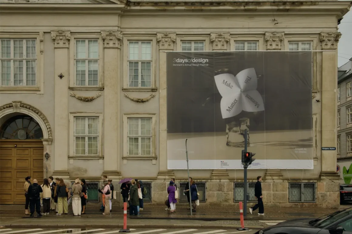 Visitatori davanti al maxi poster di 3daysofdesign Copenhagen 2026 sul palazzo storico di Kongens Nytorv