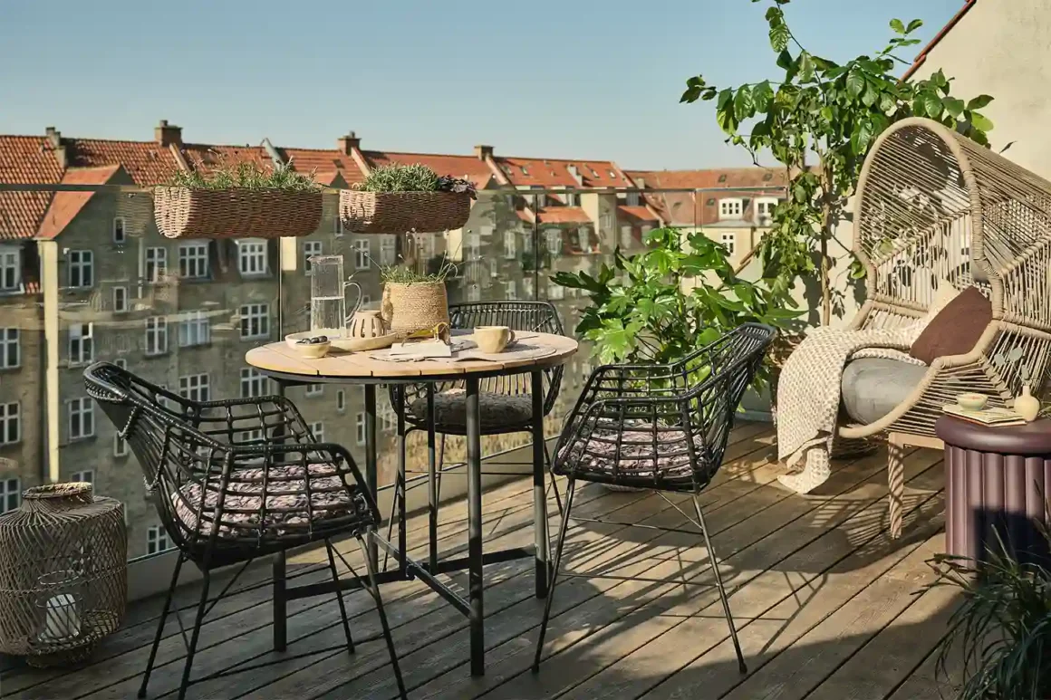 Idee per il balcone con tavolo rotondo HOVVIG, sedie ILDERHUSE in rattan nero e piante – collezione outdoor JYSK