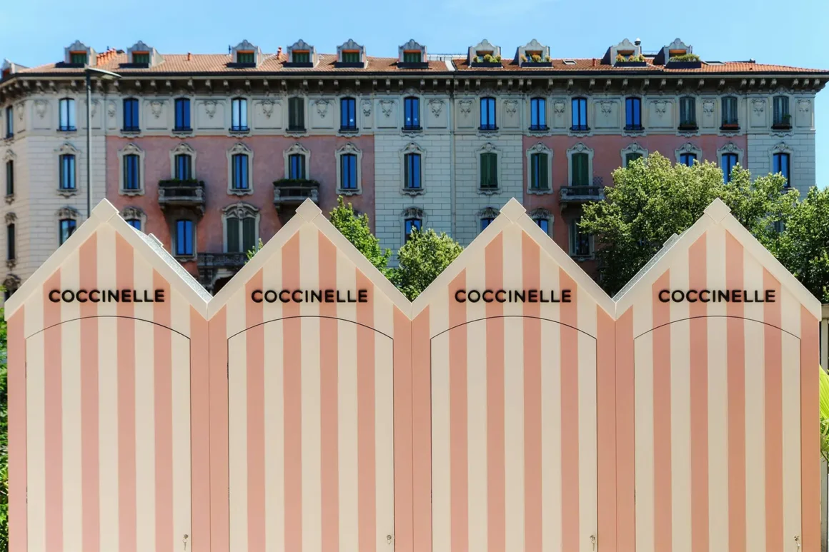 Cabine da spiaggia Coccinelle at Tommasi a righe rosa davanti a un palazzo storico di Milano