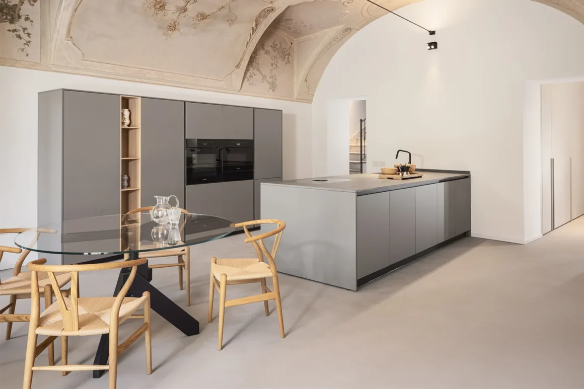 Pavimento in microcemento grigio continuo in cucina open space con isola e soffitto a volta affrescato
