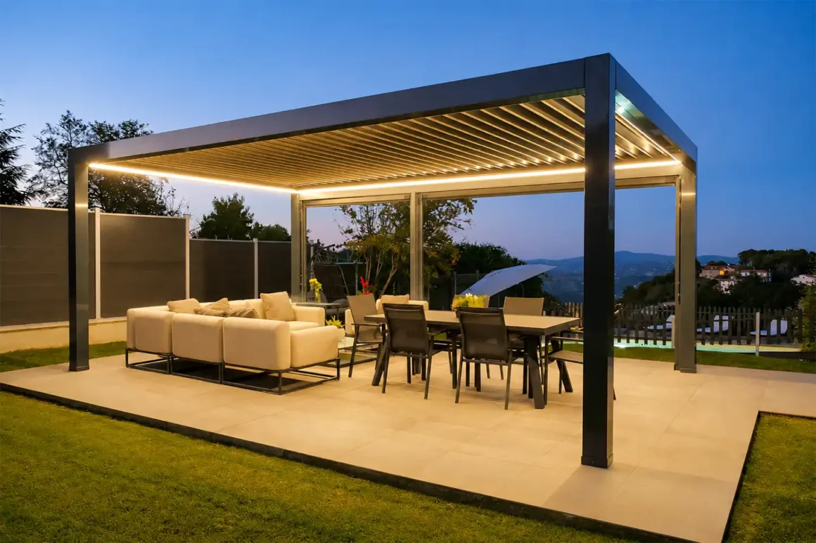 Pergola bioclimatica in alluminio con zona living e pranzo illuminata la sera