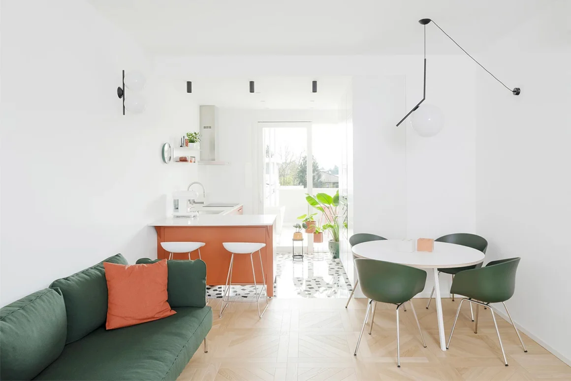 Casa PaCa di Later Studio: open space con parquet a quadrotte, divano verde e cucina color terracotta