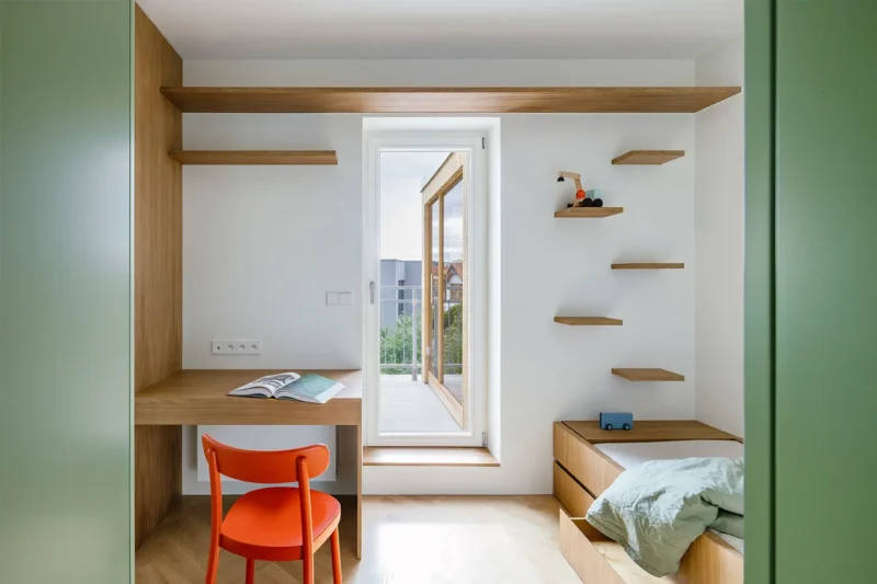 Il cubo verde che riorganizza lo spazio: dentro un piccolo appartamento a Praga 3 Angolo studio con scrivania a incasso e mensole nella cameretta trasformabile