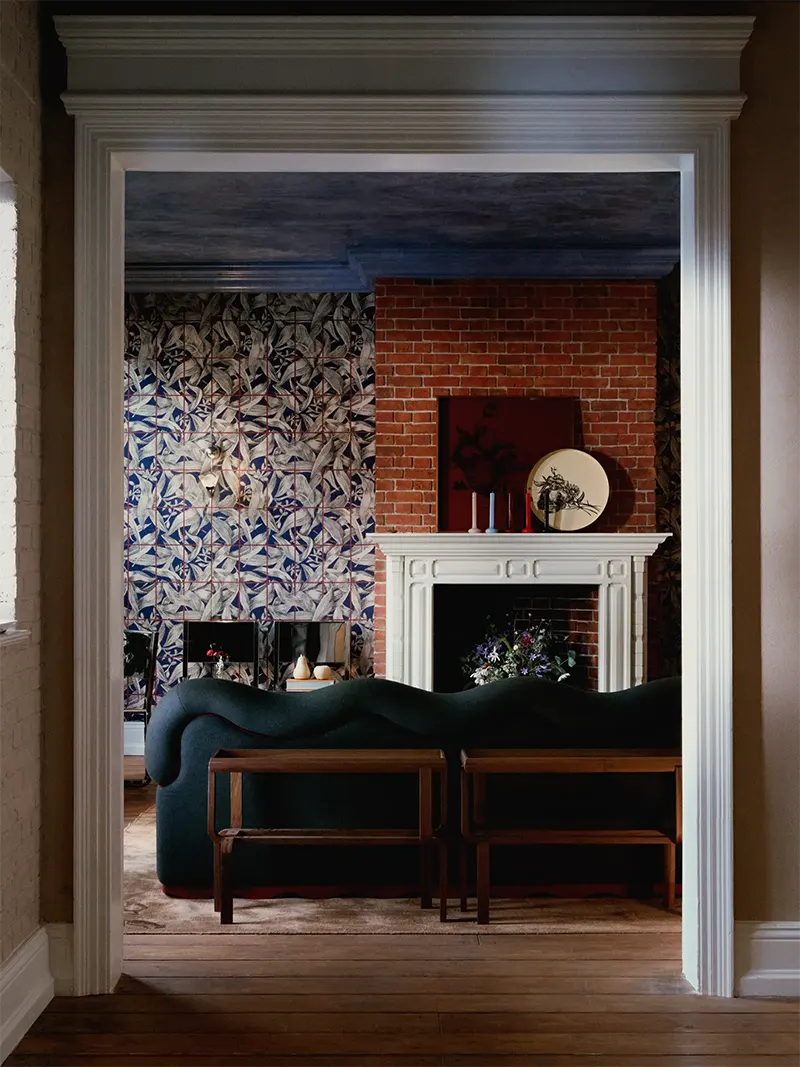 Salotto con camino in mattoni e divano verde della collezione Atlas of Desire Zara Home