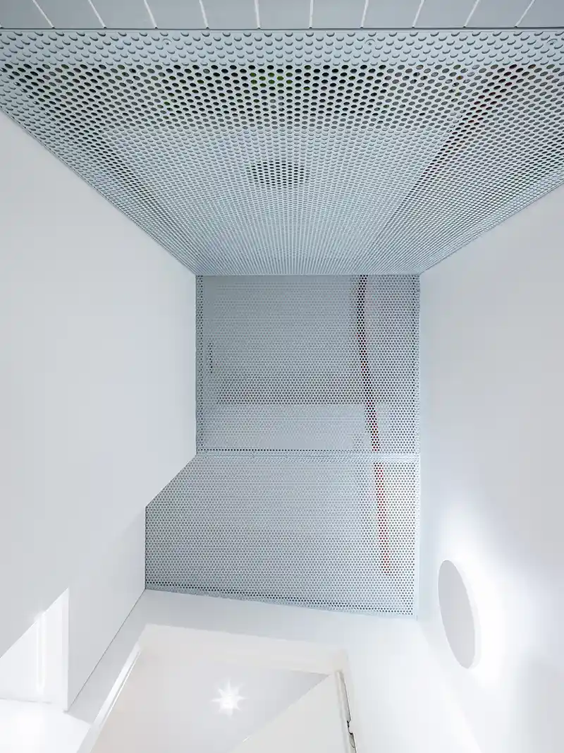 Il cubo verde che riorganizza lo spazio: dentro un piccolo appartamento a Praga 7 Dettaglio del soffitto microforato nella zona sauna sulla terrazza