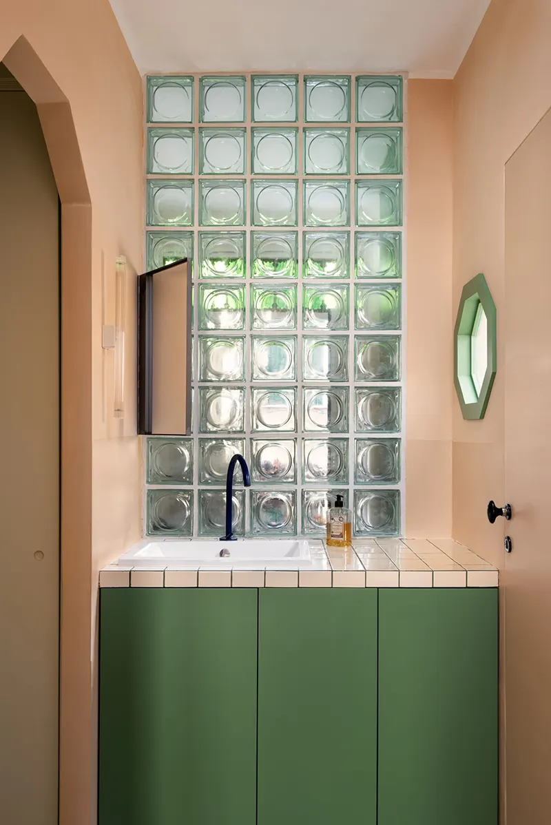 Vetrocemento colorato verde abbinato a pareti terracotta e mobile lavabo in un bagno ristrutturato a Roma Trastevere
